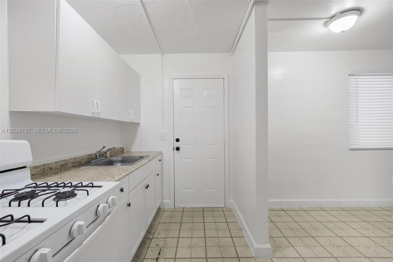 A kitchen features white cabinets, a gas stove, a sink, and tiled flooring — 126 SW 18th Ave # 4, Miami FL 33135, MIAMI, FL