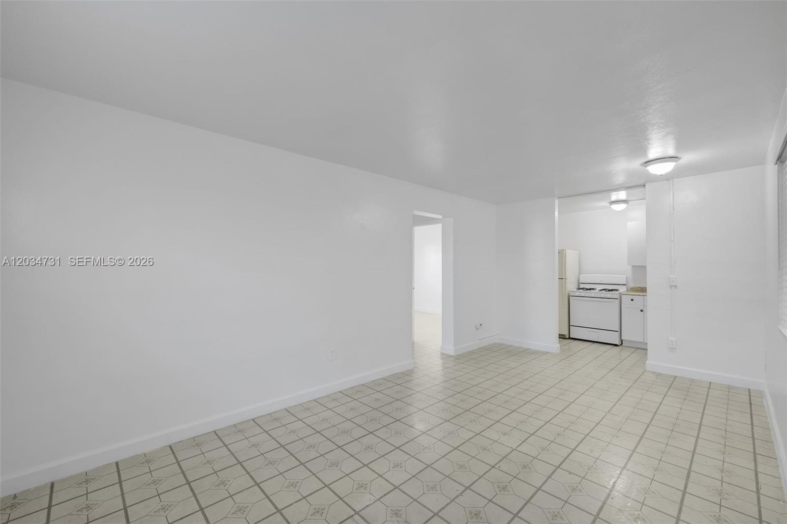 A white-walled room features light-colored tiled flooring and an open doorway leading to a kitchen — 126 SW 18th Ave # 4, Miami FL 33135, MIAMI, FL