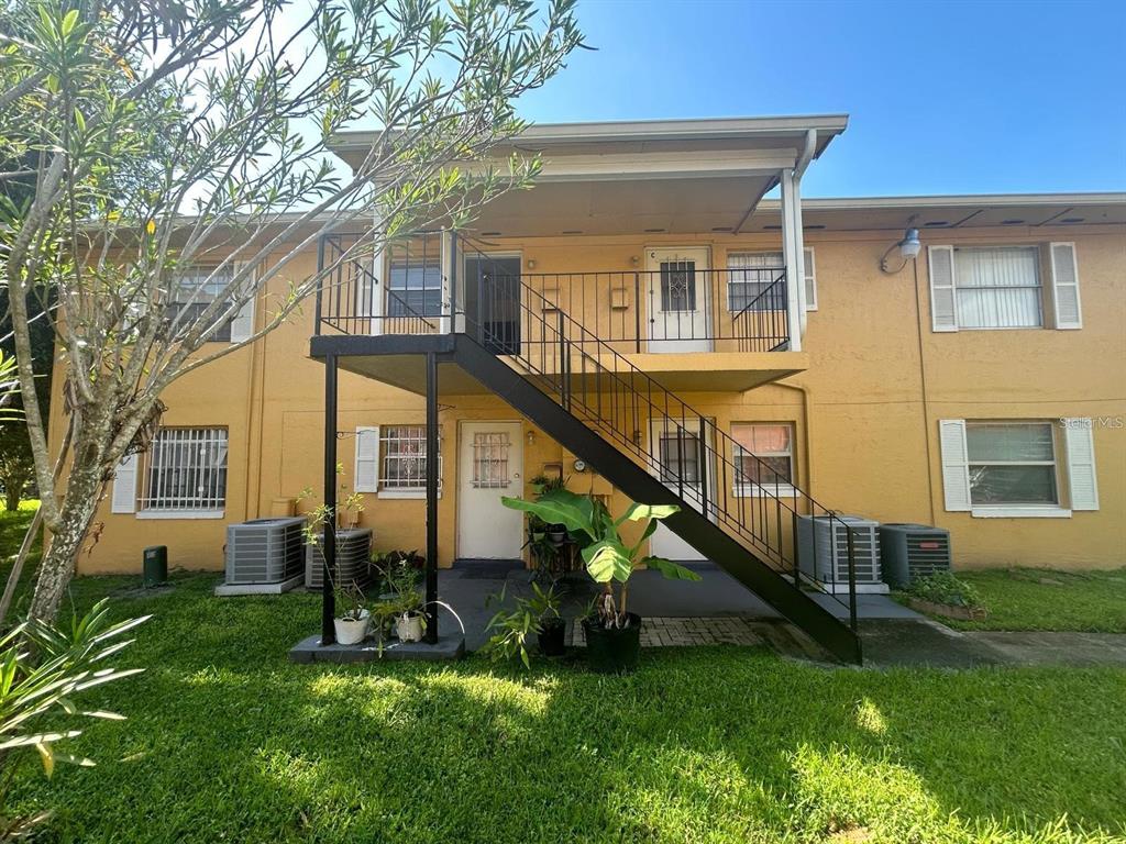 Exterior view of a two-story apartment building with a metal staircase leading to a balcony — 1627 W OAK RIDGE ROAD UNIT D, ORLANDO, FL
