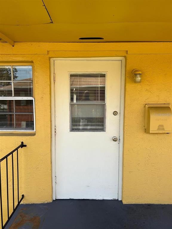 A white door with a window sits on a yellow exterior wall next to a mailbox — 1627 W OAK RIDGE ROAD UNIT D, ORLANDO, FL