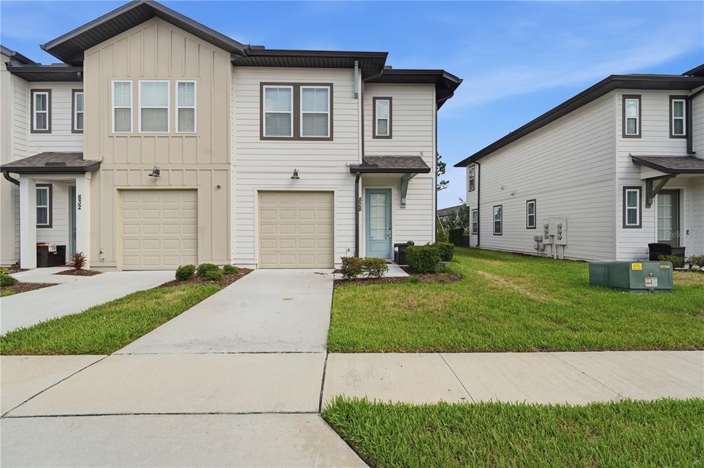 A two-story townhouse exterior features light siding, a single-car garage, and a concrete driveway — 828 LONGBOAT DRIVE, DAVENPORT, FL