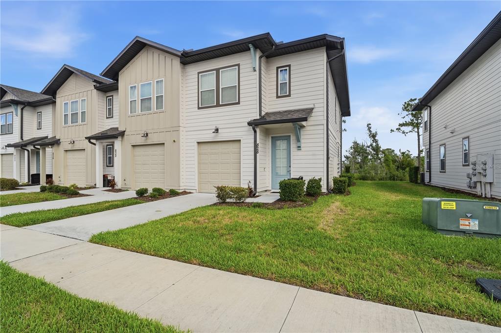 A two-story townhouse with light siding, a single-car garage, and a blue front door — 828 LONGBOAT DRIVE, DAVENPORT, FL