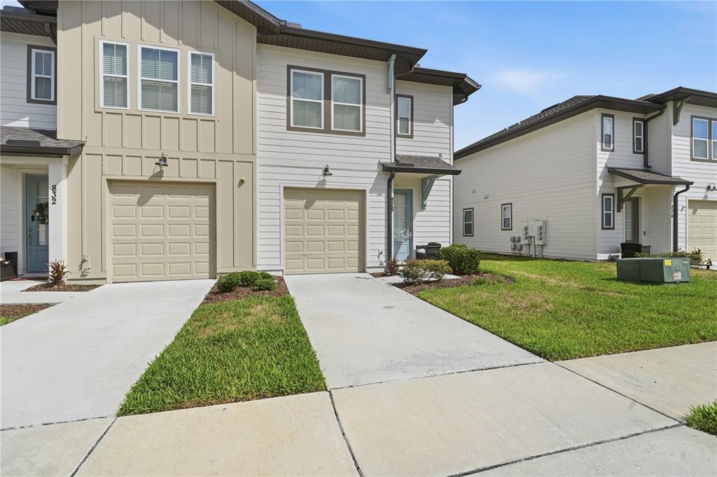 Two adjacent two-story townhouses feature light-colored siding, single-car garages, and concrete driveways — 828 LONGBOAT DRIVE, DAVENPORT, FL