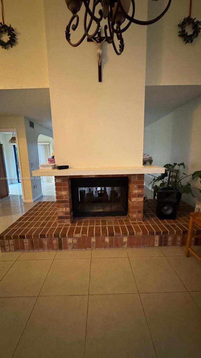 A living room features a brick fireplace with a white mantel and a hanging chandelier — 15039 SW 89th Terr Rd, Miami FL 33196, MIAMI, FL