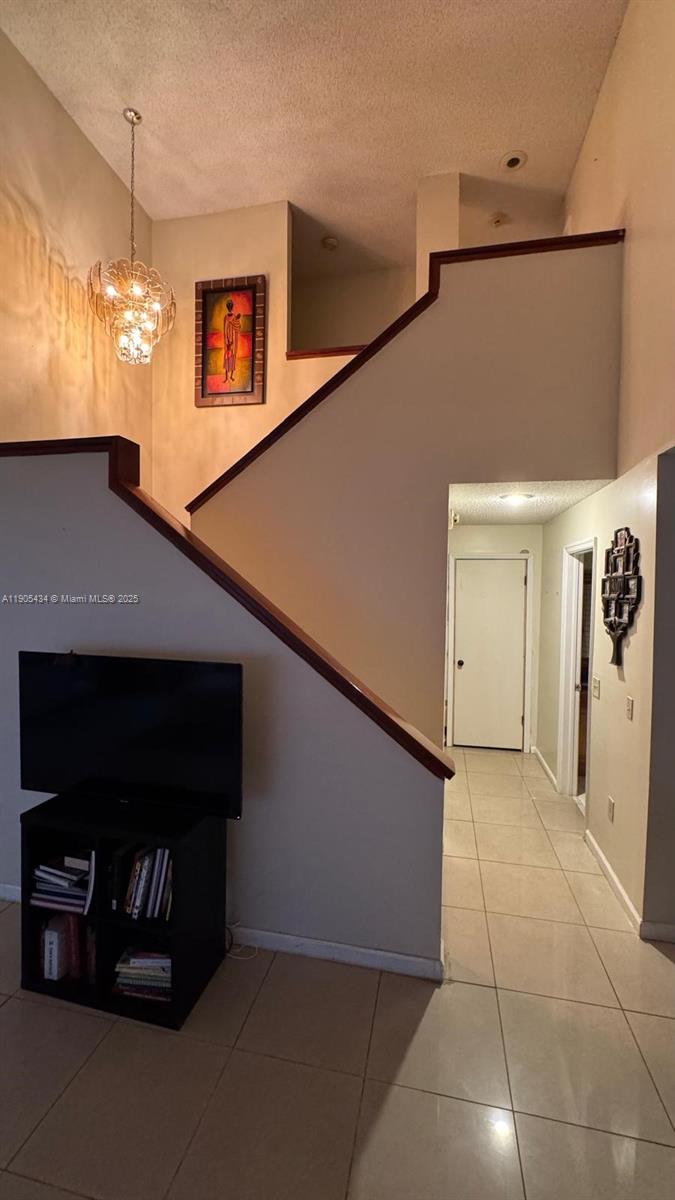 An interior view shows a staircase with a wooden railing, a chandelier, and tiled flooring — 15039 SW 89th Terr Rd, Miami FL 33196, MIAMI, FL