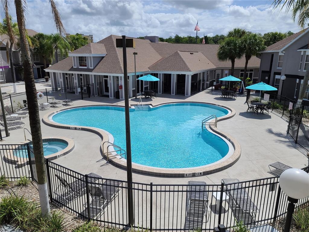 An outdoor swimming pool with a hot tub is surrounded by a patio and building — 3100 PARKWAY BOULEVARD UNIT 315, KISSIMMEE, FL