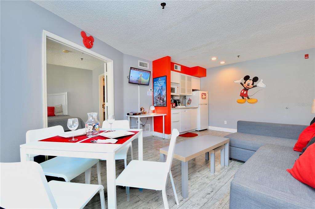 A living room and dining area featuring a kitchenette, Mickey Mouse decor, and light flooring — 3100 PARKWAY BOULEVARD UNIT 315, KISSIMMEE, FL