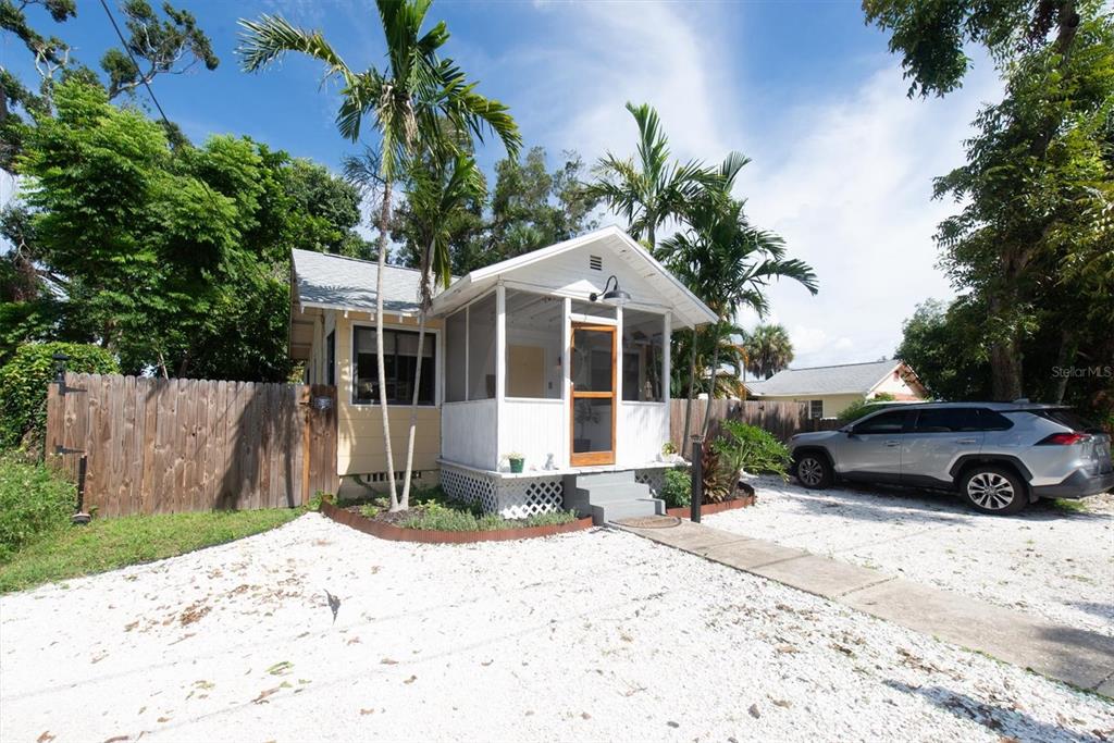 A small, yellow cottage with a screened-in front porch sits on a gravel driveway — 1840 51ST STREET S, GULFPORT, FL