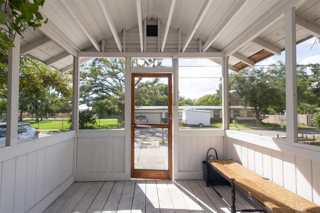 A screened-in porch with white wooden walls, exposed ceiling beams, and a wooden bench — 1840 51ST STREET S, GULFPORT, FL
