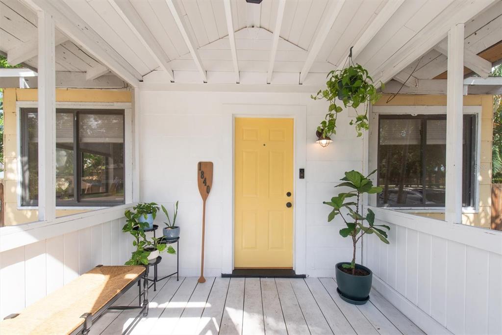 A front porch features a yellow door, a wooden oar address sign, and potted plants — 1840 51ST STREET S, GULFPORT, FL