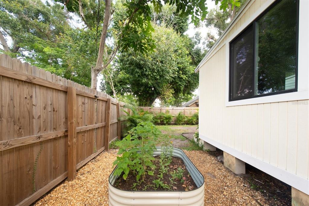 A side yard features a metal raised garden bed, gravel ground, and a wooden fence — 1840 51ST STREET S, GULFPORT, FL