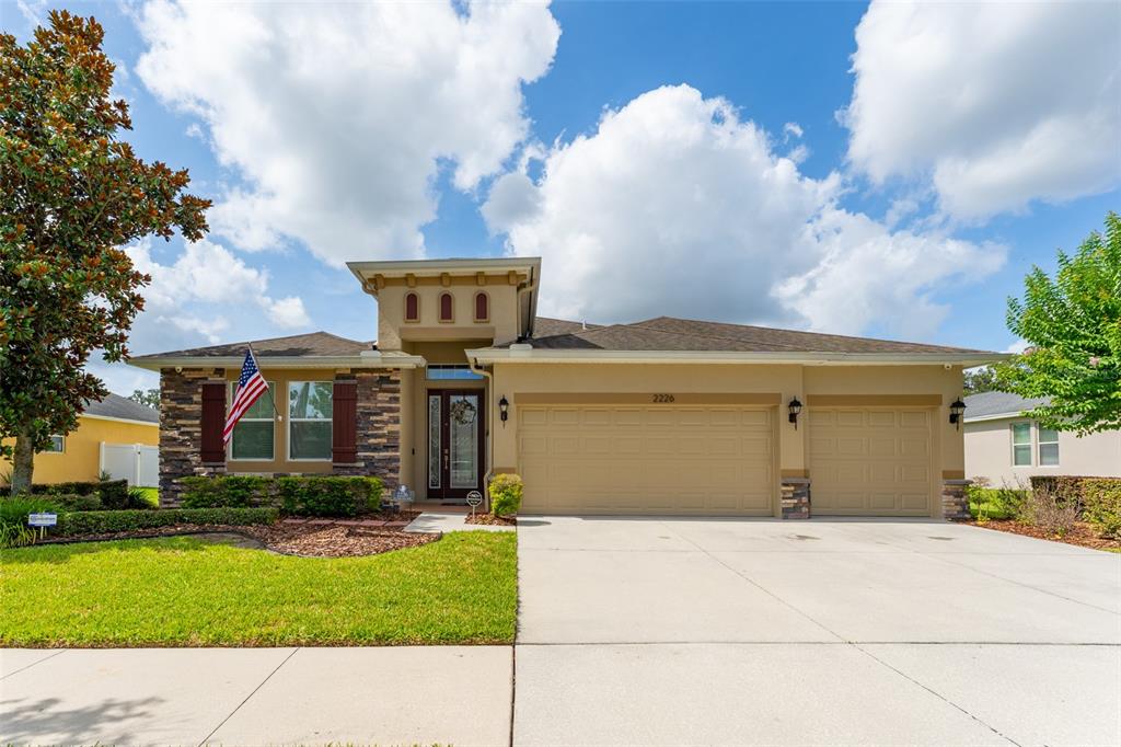 A single-story suburban house features a stone facade, a three-car garage, and a front lawn — 2226 VALTERRA VISTA WAY, VALRICO, FL