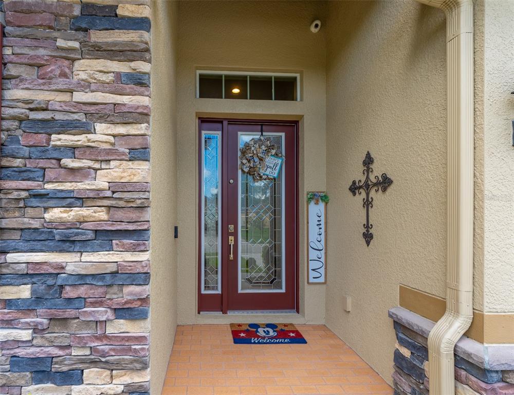 A front entryway features a red door with glass panels, stone siding, and a welcome mat — 2226 VALTERRA VISTA WAY, VALRICO, FL