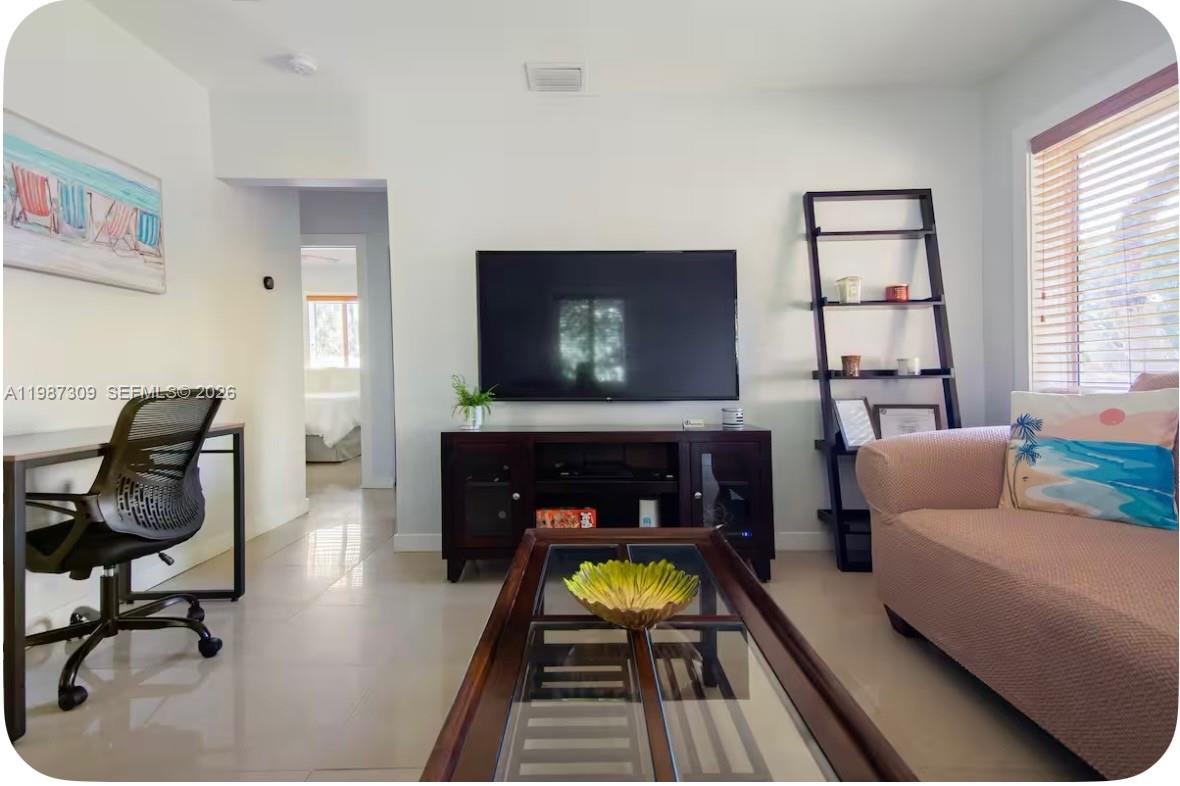 A living room features a television, media console, desk, and sofa on tiled flooring — 601 NW 116th St, Miami FL 33168, MIAMI, FL