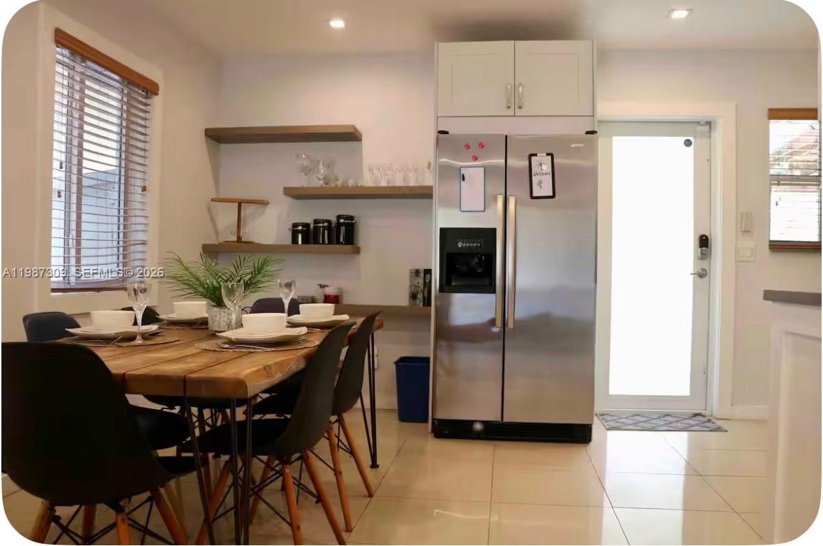 A dining area features a wooden table, floating shelves, and a stainless steel refrigerator — 601 NW 116th St, Miami FL 33168, MIAMI, FL