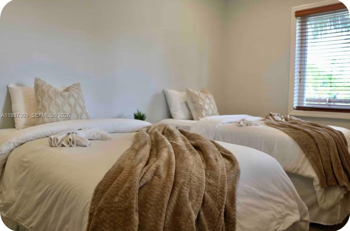 A bedroom features two twin beds with white bedding and tan throw blankets — 601 NW 116th St, Miami FL 33168, MIAMI, FL