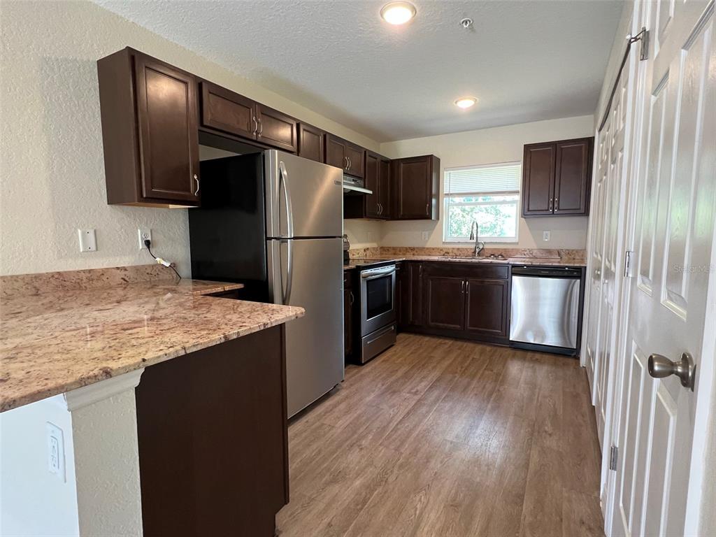 A kitchen featuring dark wood cabinets, stainless steel appliances, and granite countertops — 8526 JUNIPER ROAD UNIT 2, OCALA, FL