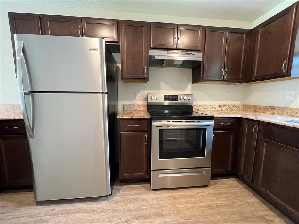 A kitchen features dark wood cabinets, stainless steel appliances, and speckled granite countertops — 8526 JUNIPER ROAD UNIT 2, OCALA, FL