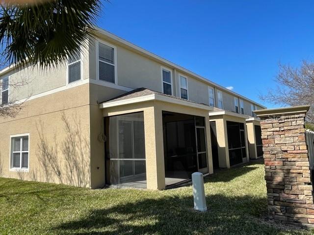 A multi-story tan townhouse features a screened-in patio and a stone pillar in the yard — 6873 47TH LANE N, PINELLAS PARK, FL