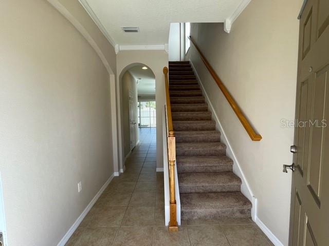 An interior view shows a tiled entryway leading to a carpeted staircase with a wooden railing — 6873 47TH LANE N, PINELLAS PARK, FL