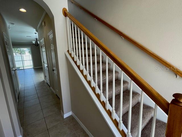 A carpeted staircase with a wooden handrail leads upward in a tiled hallway — 6873 47TH LANE N, PINELLAS PARK, FL