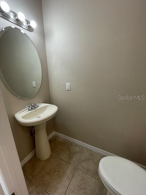 A half bathroom features a pedestal sink, an oval mirror, and light-colored tile flooring — 6873 47TH LANE N, PINELLAS PARK, FL