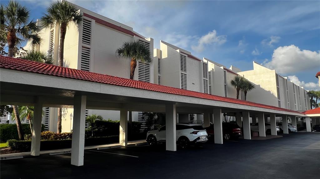 A white multi-story building with a red tile roof and a covered parking area — 7871 SAILBOAT KEY BOULEVARD S UNIT 108, ST PETERSBURG, FL