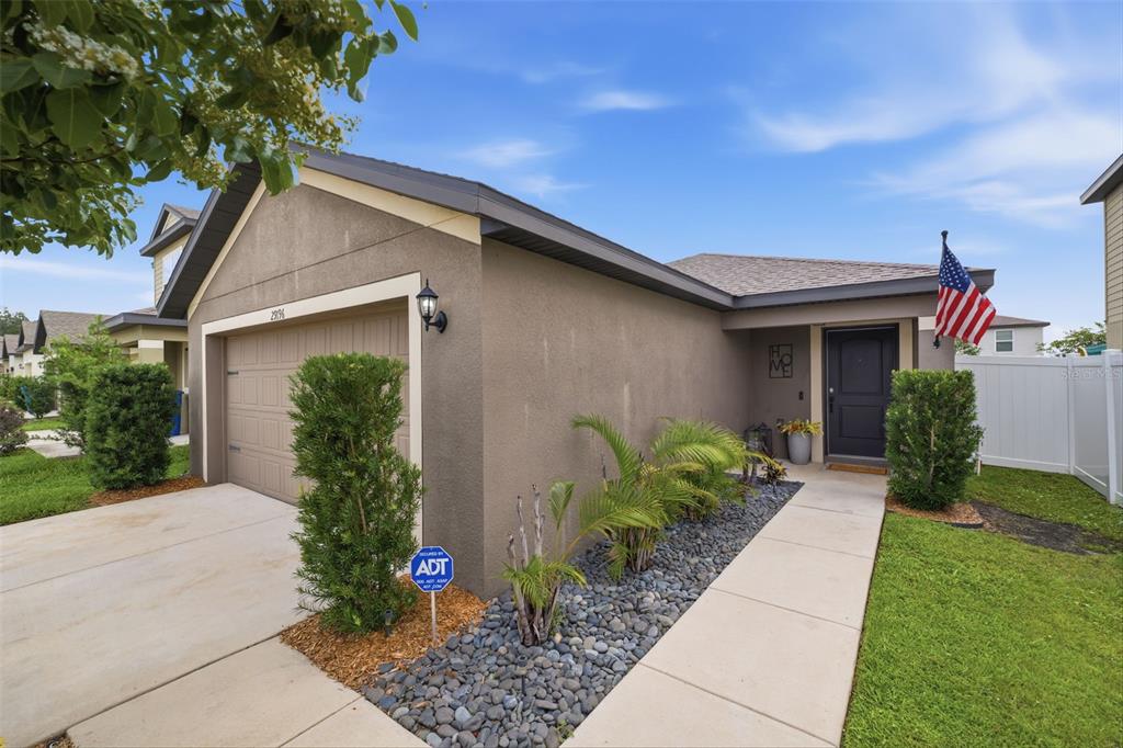 A single-story house with a tan stucco exterior, a two-car garage, and a front walkway — 29196 FEDORA CIRCLE, BROOKSVILLE, FL