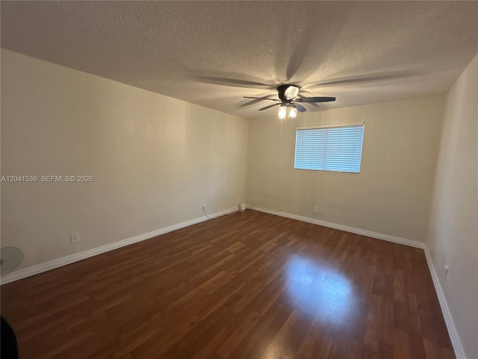 An empty room features light-colored walls, wood-look flooring, and a ceiling fan with lights — 1717 Rodman St # 18, Hollywood FL 33020, HOLLYWOOD, FL
