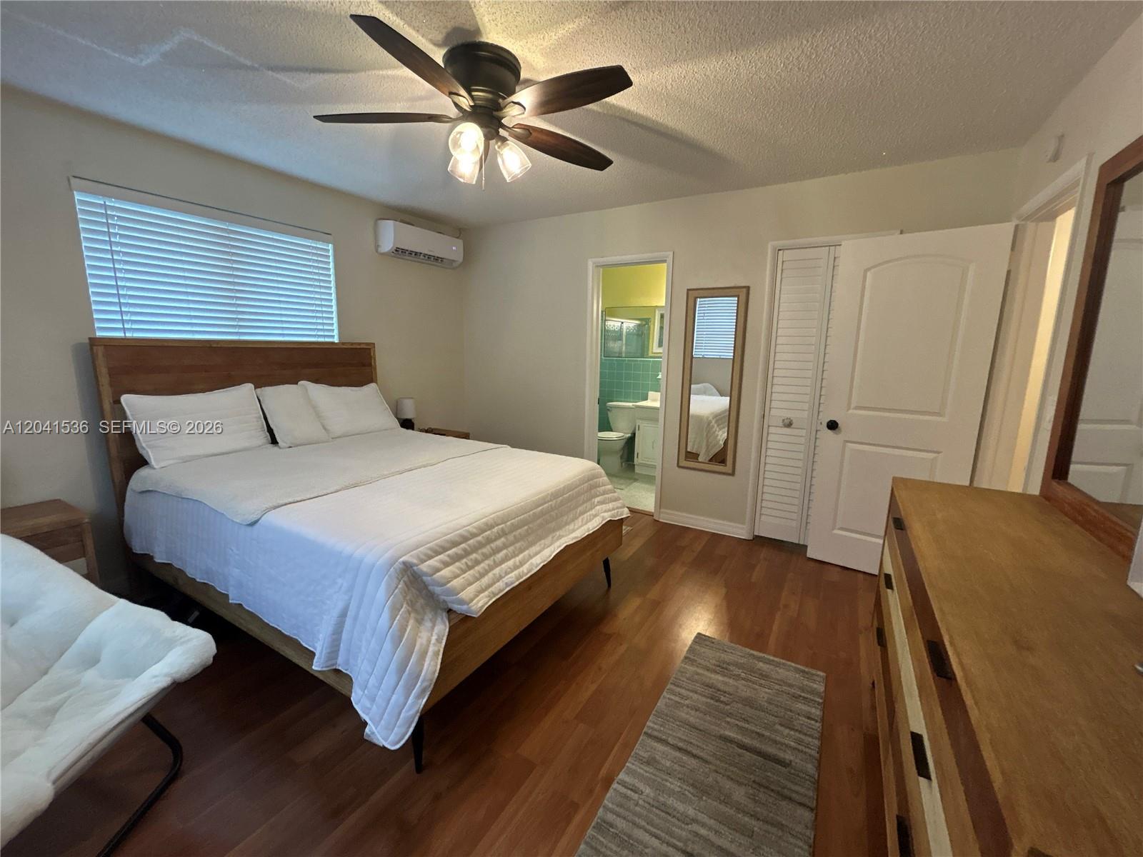 A bedroom features a wooden bed frame, hardwood floors, a ceiling fan, and an attached bathroom — 1717 Rodman St # 18, Hollywood FL 33020, HOLLYWOOD, FL