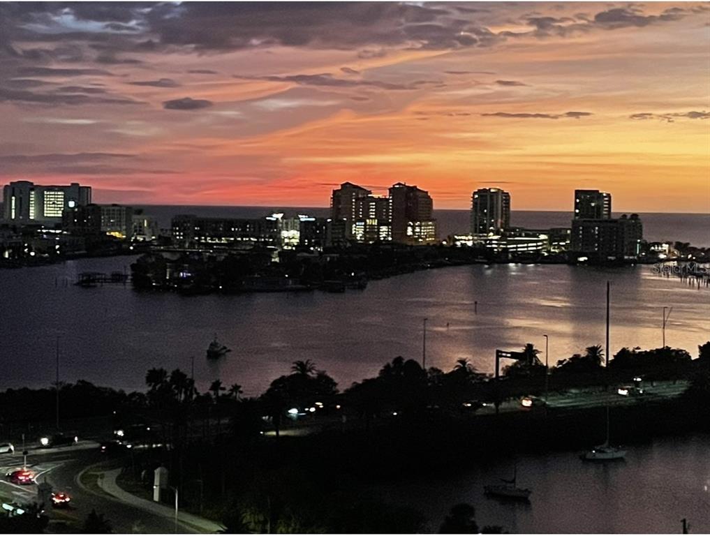 An elevated view of a coastal city skyline across a bay during a sunset — 31 ISLAND WAY UNIT 1403, CLEARWATER BEACH, FL