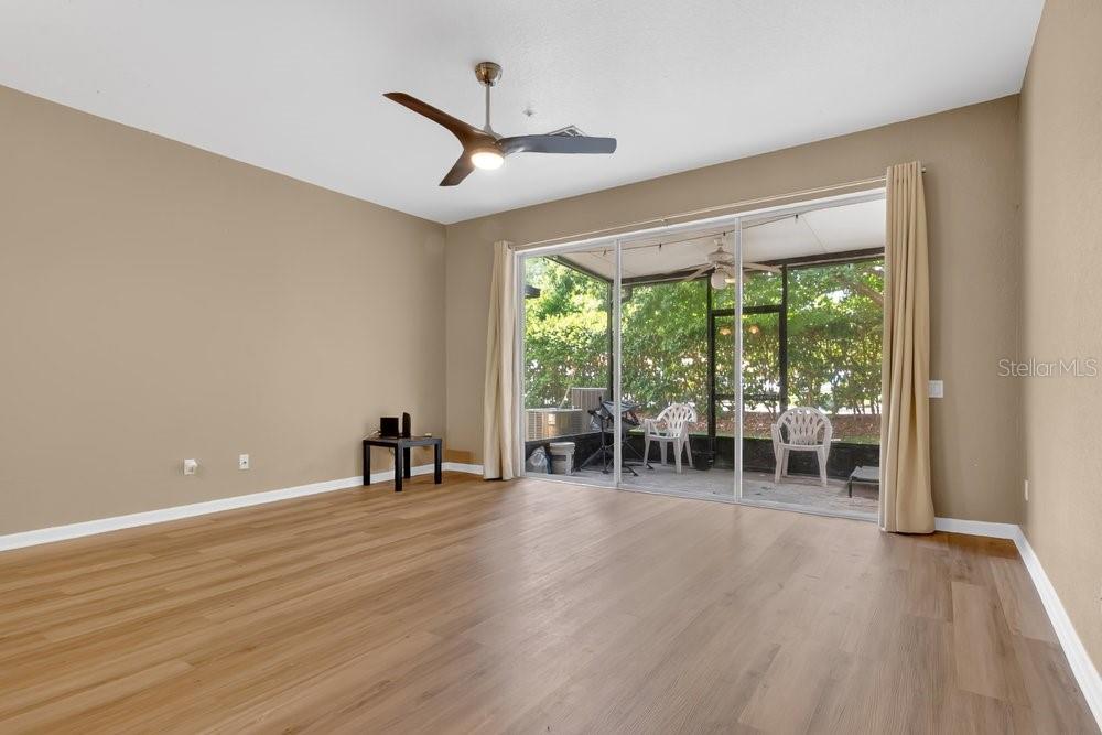 An empty living room with light wood-look flooring and a sliding glass door to a patio — 6302 DAYSBROOK DRIVE UNIT 104, ORLANDO, FL