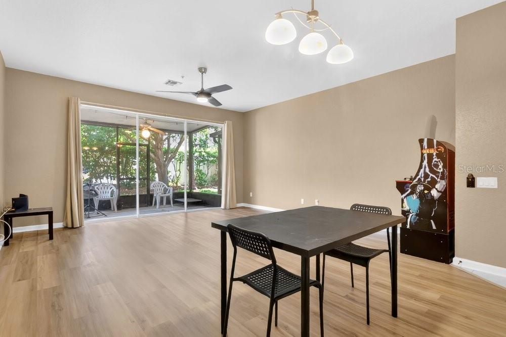 A dining area with wood-look flooring, a table, chairs, and an arcade game cabinet — 6302 DAYSBROOK DRIVE UNIT 104, ORLANDO, FL