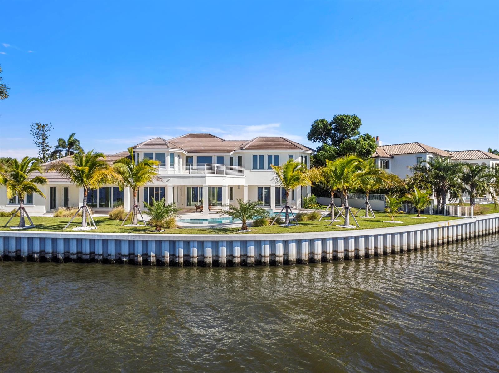 A large waterfront house with a pool, palm trees, and a white bulkhead wall — 526 Point Lane, Vero Beach FL 32963, VERO BEACH, FL