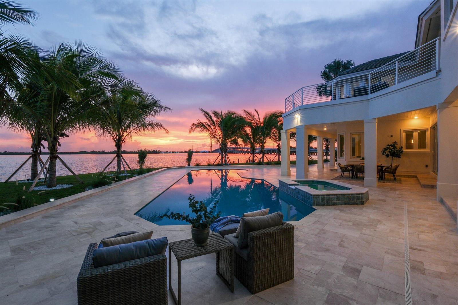 A luxury waterfront home features a swimming pool, patio, and palm trees at sunset — 526 Point Lane, Vero Beach FL 32963, VERO BEACH, FL