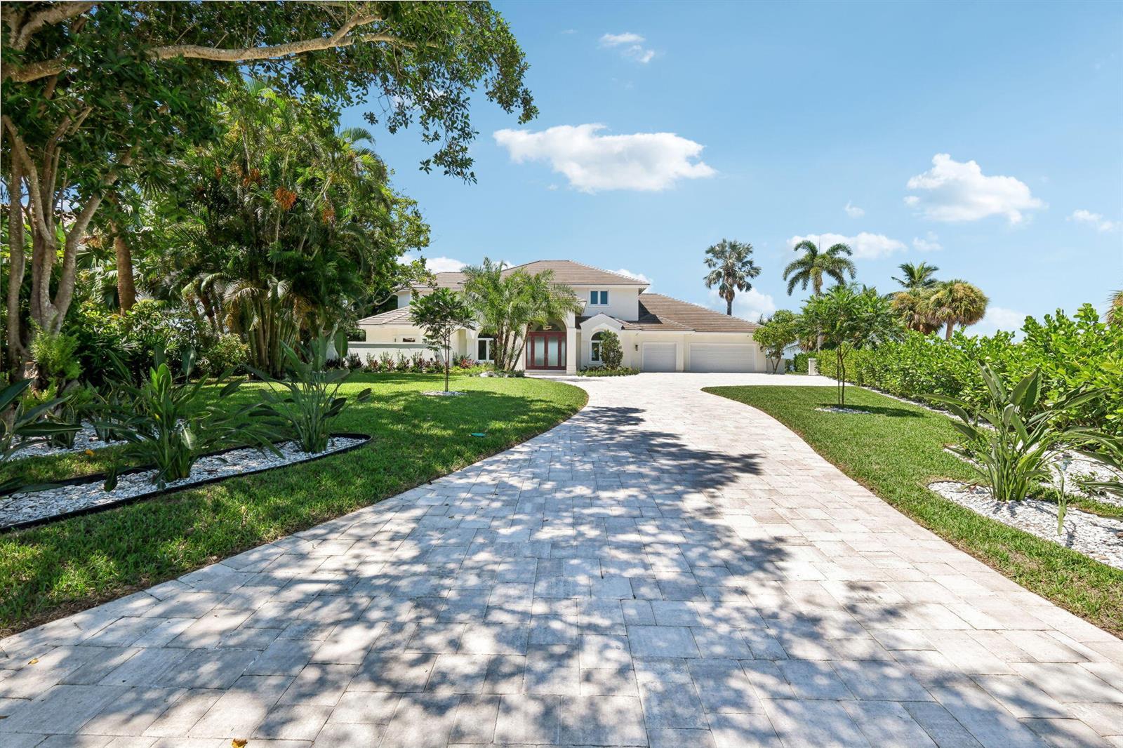 A paved driveway leads to a two-story house with a multi-car garage and landscaping — 526 Point Lane, Vero Beach FL 32963, VERO BEACH, FL