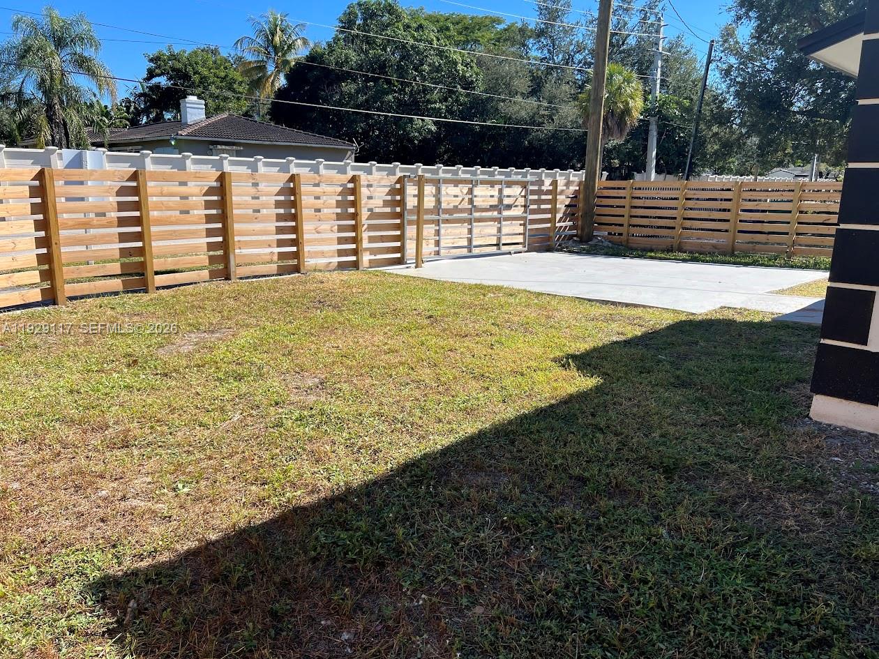 A backyard features a wooden horizontal fence, a concrete driveway, and a metal sliding gate — 9254 NW 3rd Ave, Miami FL 33150, MIAMI, FL