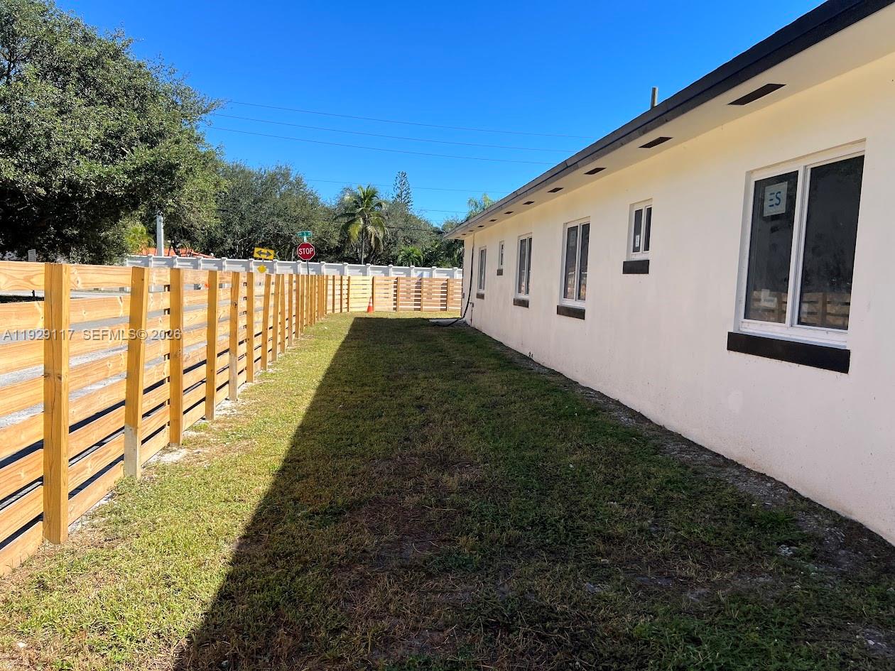 A side yard features a wooden fence, a grassy lawn, and the exterior of a house — 9254 NW 3rd Ave, Miami FL 33150, MIAMI, FL
