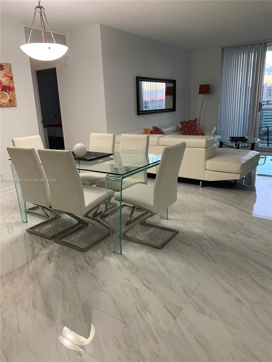 A dining area with a glass table and chairs sits before a white sectional sofa — 3901 S Ocean Dr # 12V, Hollywood FL 33019, HOLLYWOOD, FL
