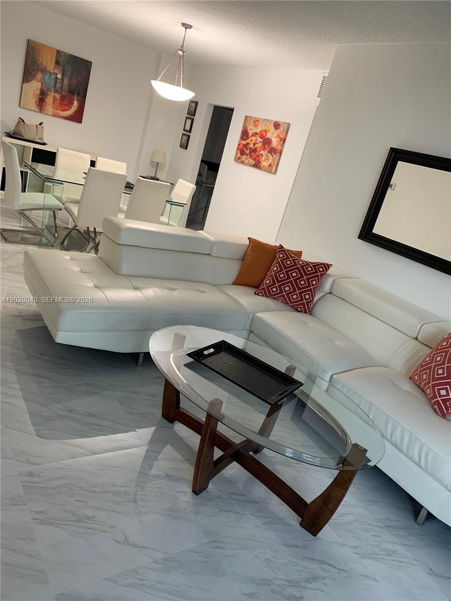 A living room features a white leather sectional, a glass coffee table, and marble flooring — 3901 S Ocean Dr # 12V, Hollywood FL 33019, HOLLYWOOD, FL