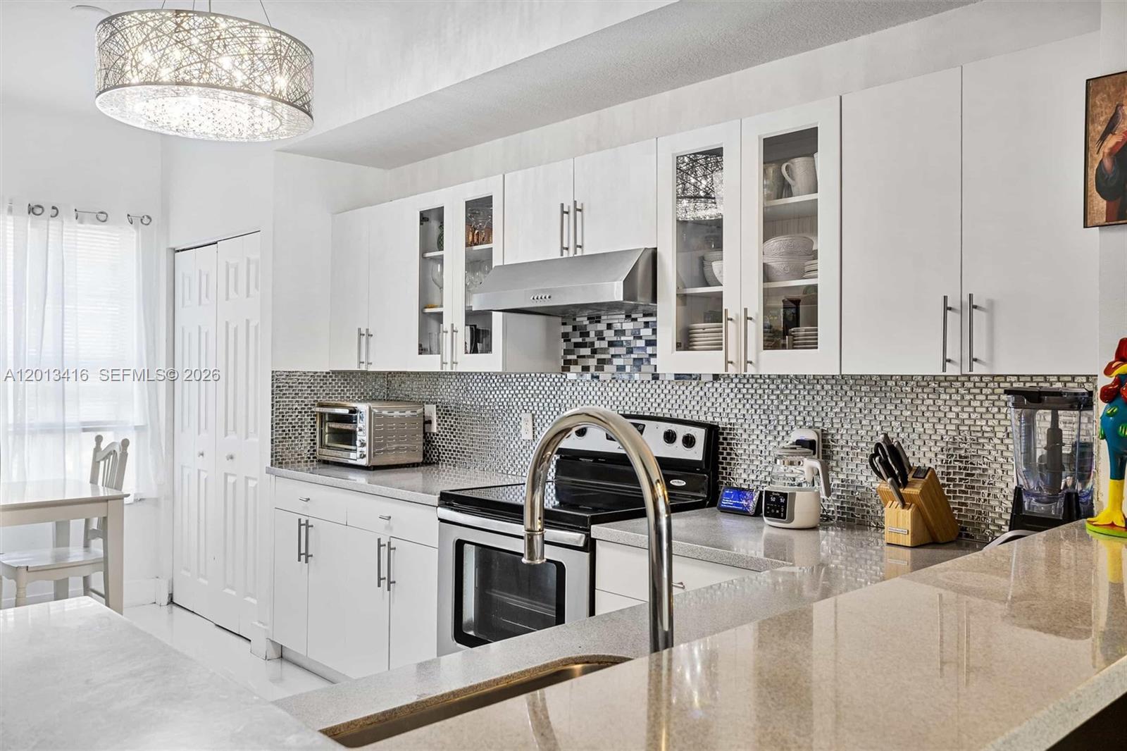 A kitchen features white cabinetry, a mosaic tile backsplash, stainless steel appliances, and granite countertops — 746 NE 90th St # 606, Miami FL 33138, MIAMI, FL