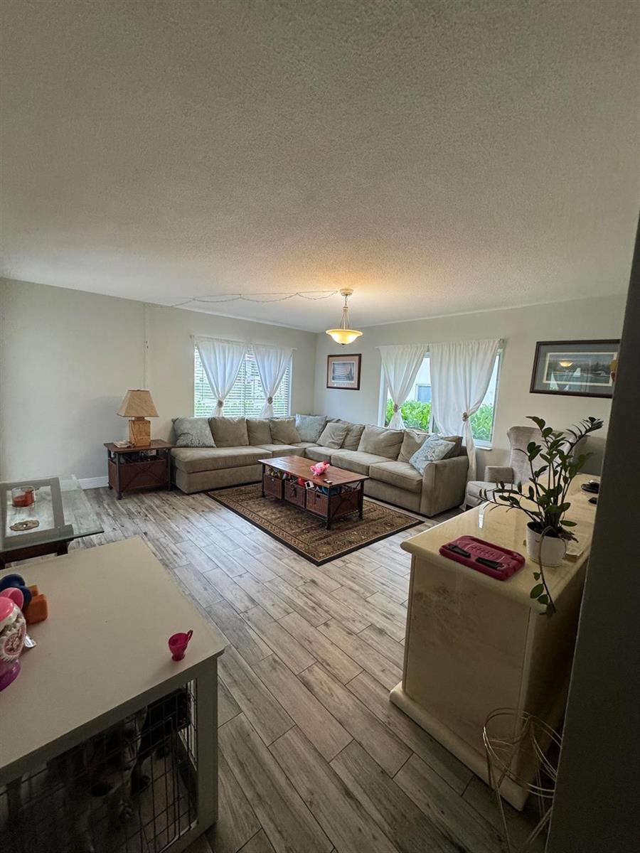A living room features a large sectional sofa, wood-look tile flooring, and a central coffee table — 225 SW 7th Street # 101, Boca Raton FL 33432, BOCA RATON, FL