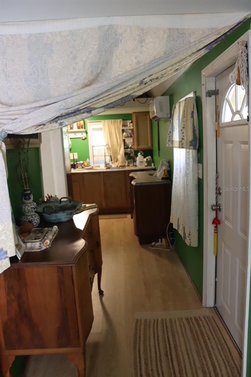 A view from a hallway looking into a kitchen with green walls and wood cabinets — 117 FRONTENAC STREET, INTERLACHEN, FL