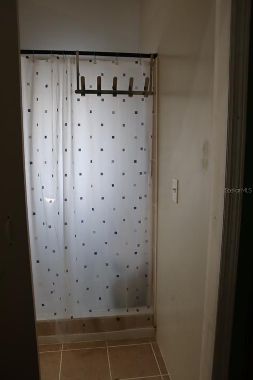 A shower stall with a white patterned curtain and a metal rack hanging above it — 117 FRONTENAC STREET, INTERLACHEN, FL
