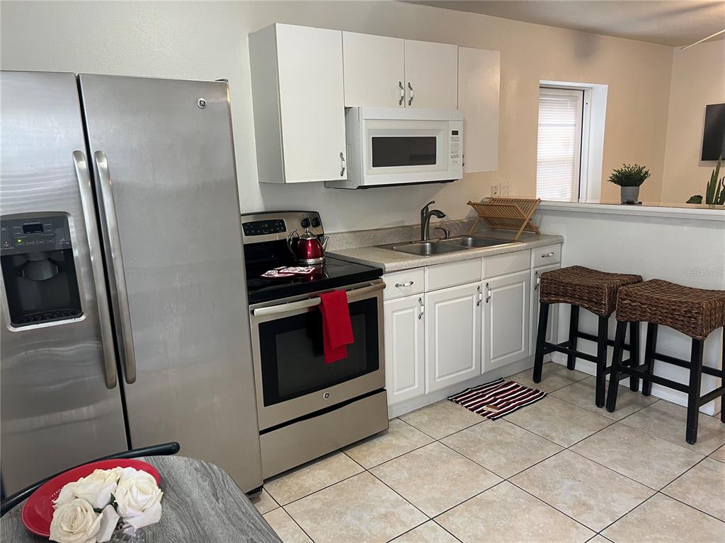 A kitchen features stainless steel appliances, white cabinets, a double sink, and tiled flooring — 1322 ARLINGTON STREET, ORLANDO, FL