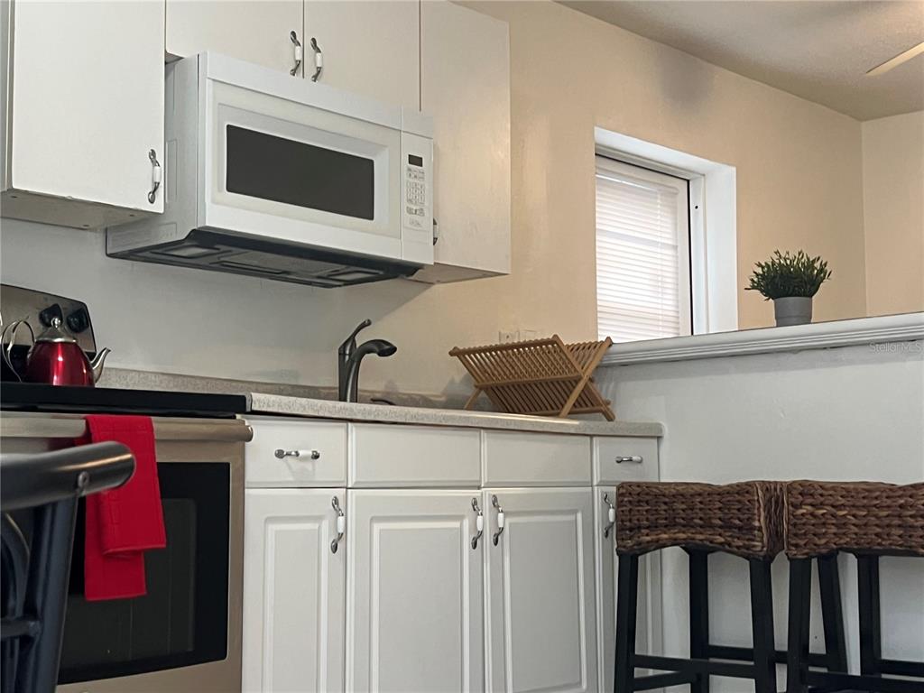 A kitchen features white cabinets, a microwave, a sink, and a breakfast bar with stools — 1322 ARLINGTON STREET, ORLANDO, FL