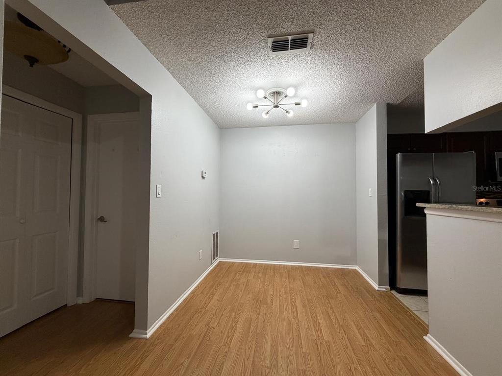 A dining area with light wood-look flooring, gray walls, and a modern sputnik-style light fixture — 8643 MALLARD RESERVE DRIVE UNIT 202, TAMPA, FL