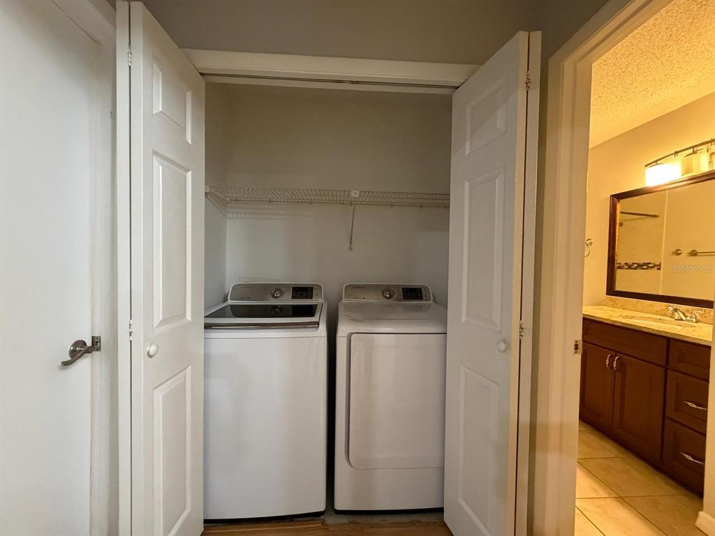 A laundry closet with a washer and dryer sits next to a bathroom vanity — 8643 MALLARD RESERVE DRIVE UNIT 202, TAMPA, FL