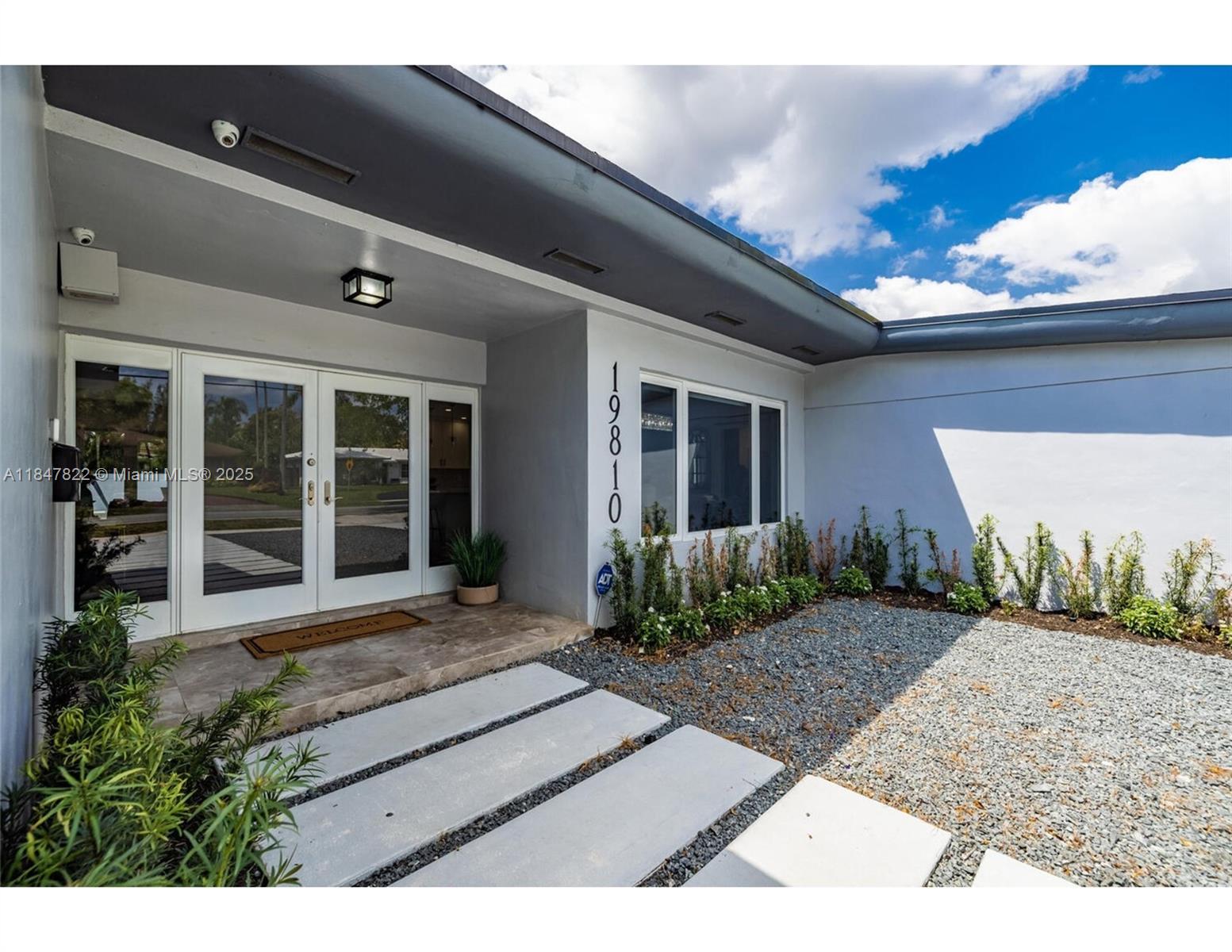 The exterior entrance features a double glass door, concrete pavers, and a gravel garden bed — 19810 NE 22nd av, Miami FL 33180, MIAMI, FL