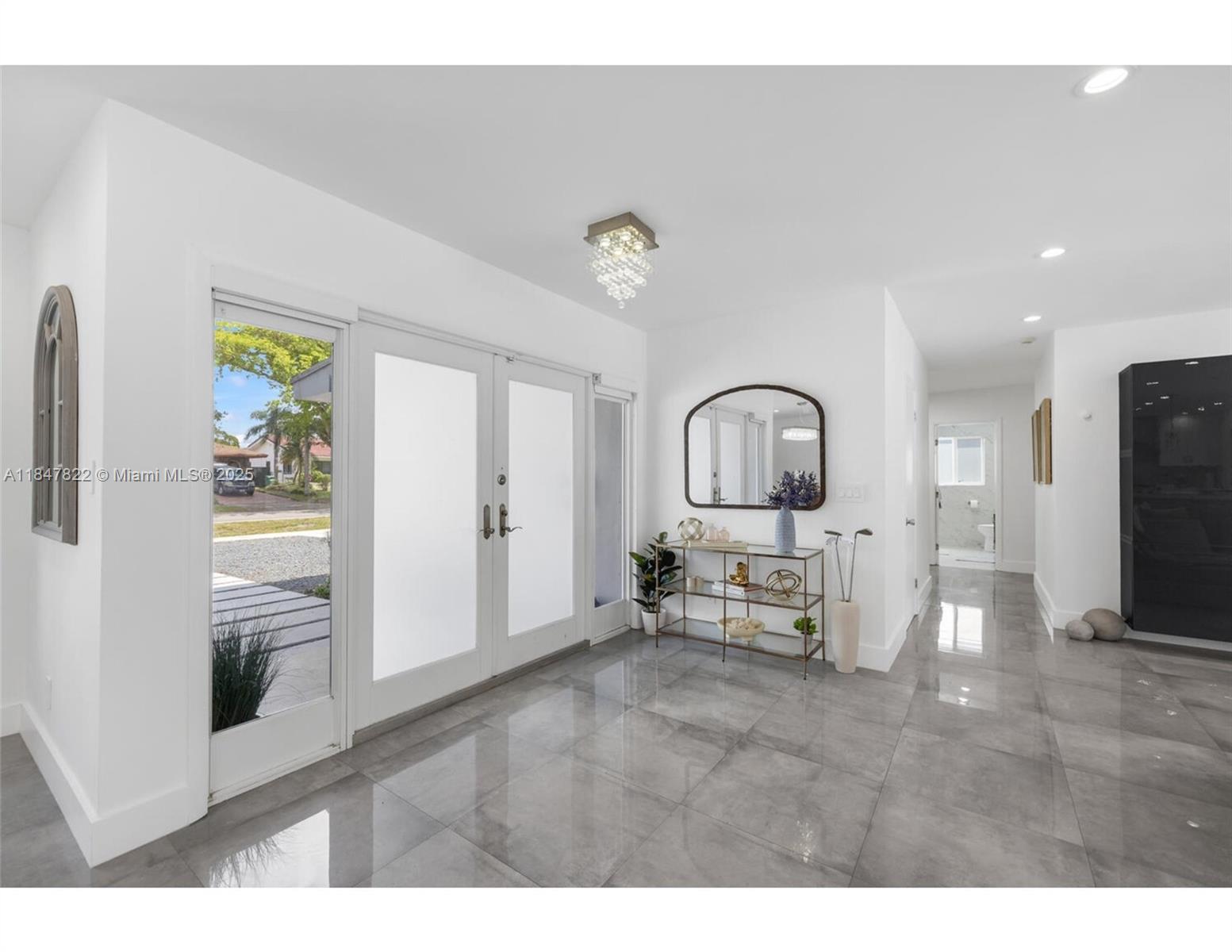 A bright entryway features gray tile floors, double glass doors, and a modern console table — 19810 NE 22nd av, Miami FL 33180, MIAMI, FL